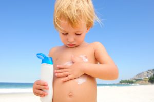child applying sunscreen to prevent skin cancer